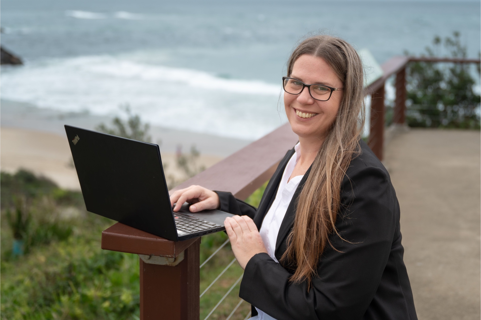 Malinda Sherrard working on her laptop at a Mid North Coast beach lookout